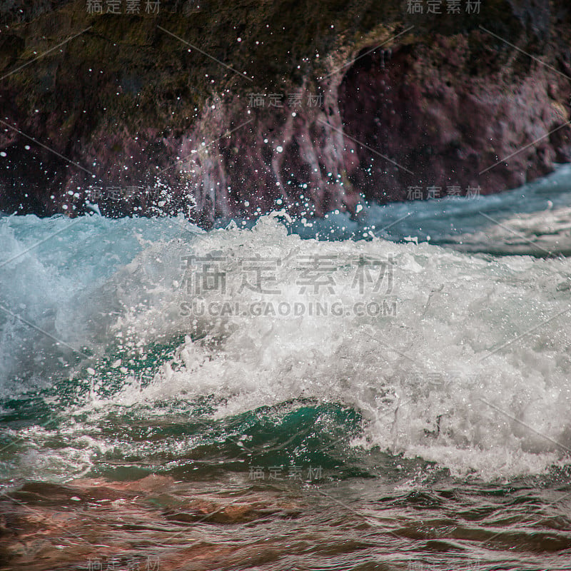 海浪拍打着海湾里的岩石。碧绿的海水和白色泡沫相遇在岸边粗糙的石头上。强大和平的自然理念。