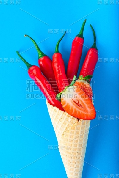 蓝色背景上的成熟的红草莓和辣椒