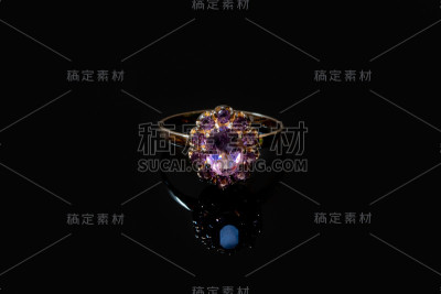 美丽的金色戒指与紫色宝石孤立在黑色背景