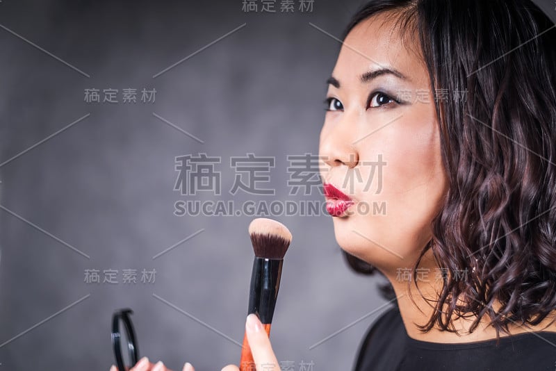 亚洲女人化妆吹在画笔工作室拍摄