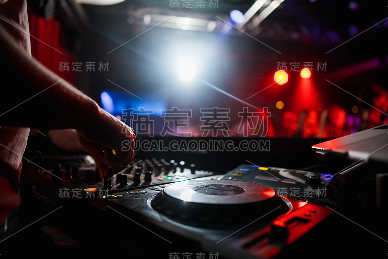 控制DJ混合音乐与模糊的人跳舞在派对在夜总会