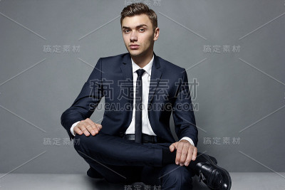 一个穿夹克打领带的男人正坐在那里看着摄像机