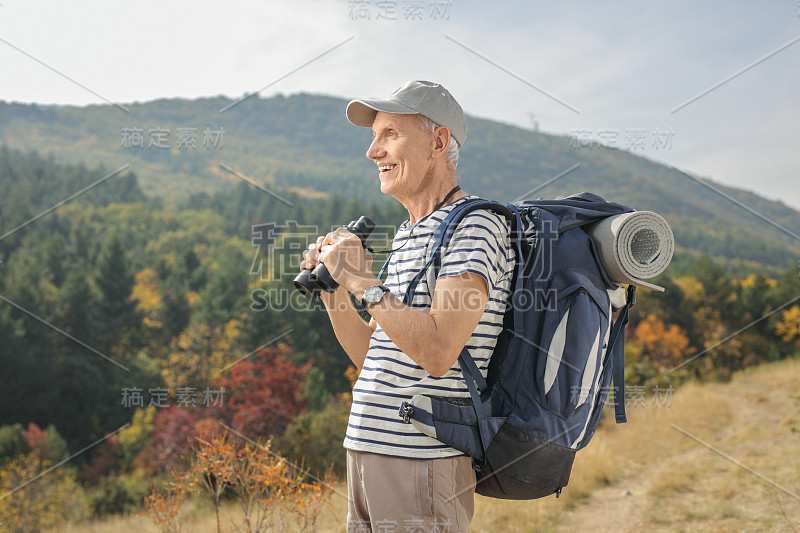 在户外拿着双筒望远镜的老年徒步旅行者