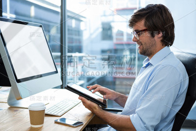 在办公桌上使用数字平板电脑的商人