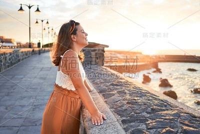 美丽的年轻女子走在海滩散步欣赏海景微笑愉快的暑假