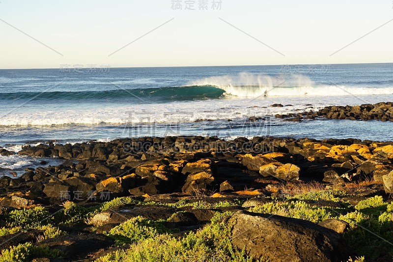 清晨阳光下的岩石冲浪海滩