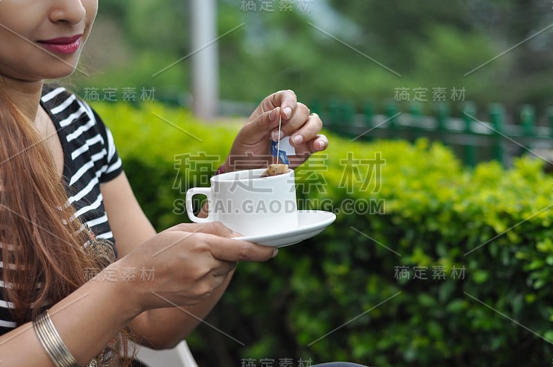 早晨在花园里喝绿茶的女人