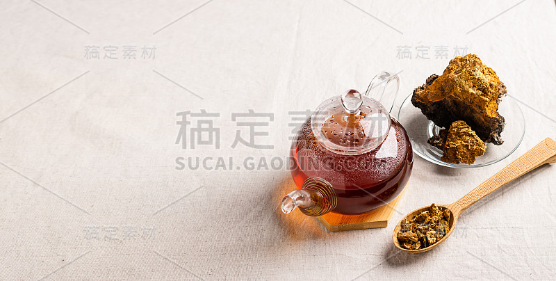 健康茶从查加树蘑菇在玻璃茶壶和玻璃。有机饮料抗氧化灰色天然背景。