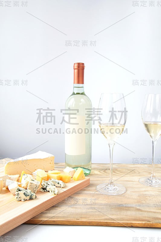 一瓶白葡萄酒，两个玻璃杯，一块木板上放着奶酪