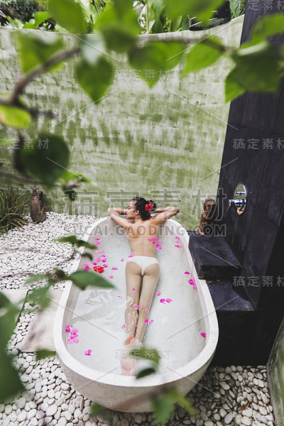 女人放松在圆形户外沐浴热带鲜花，有机皮肤护理，豪华水疗酒店，生活方式照片