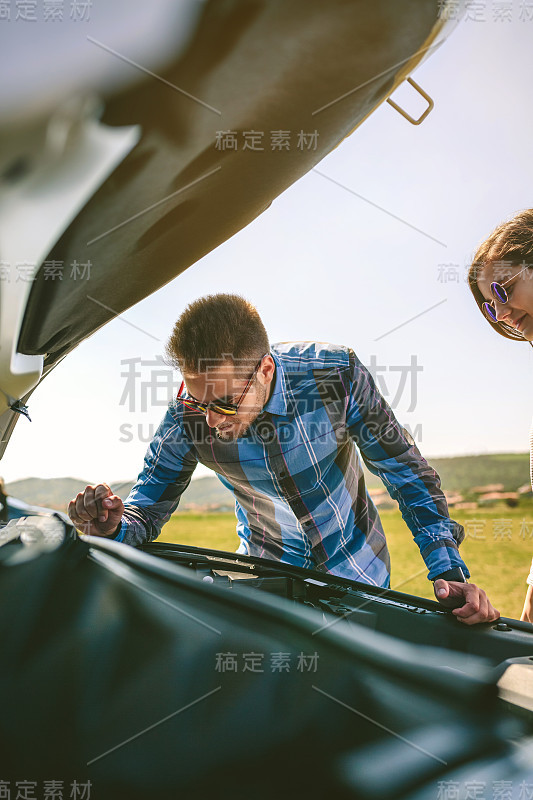 一对年轻夫妇试图修理出故障的汽车