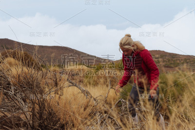小女孩穿着夹克在草原景观中徒步旅行
