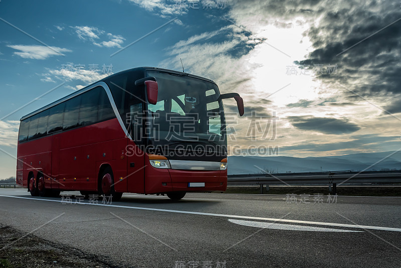 红色现代旅游巴士在明媚的阳光下行驶在高速公路上