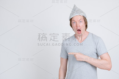 震惊的年轻人用锡纸帽子指着一边作为阴谋论的概念