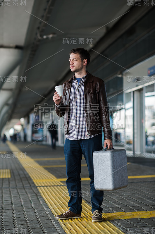 年轻有魅力的男人喝咖啡在他的路上