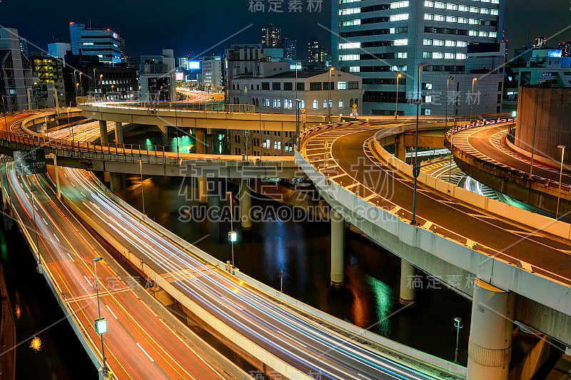 在日本东京，繁忙的西新宿高速公路十字路口的全景与灯光小径在夜间