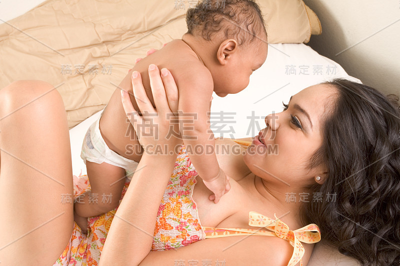 拉丁母亲和她的小儿子在床上玩