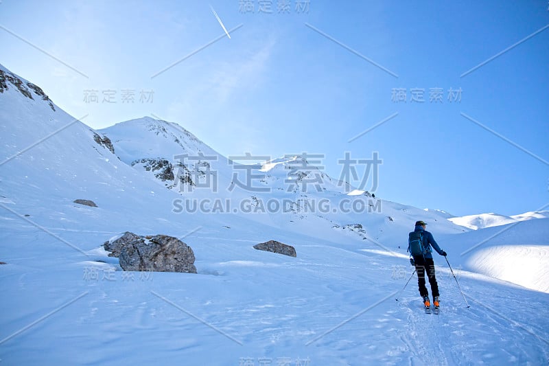 在一个阳光明媚的日子里，一个人在比利牛斯山的群山中滑雪旅行