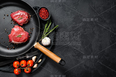 生菲力牛排在煎锅。牛肉里脊。黑色背景。前视图。空间的文本