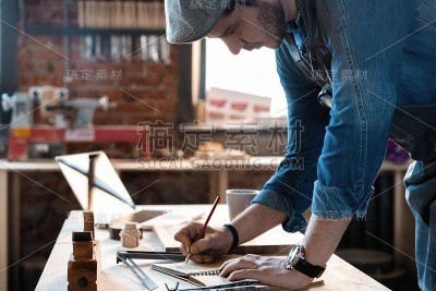 成功英俊的商人与时髦的帽子工作在木工