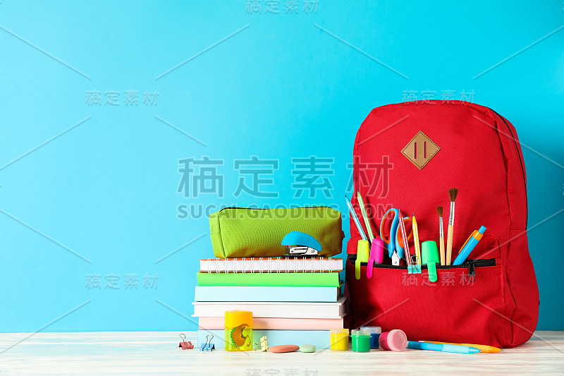 学校用品放在木桌上，以彩色为背景，留出文字空间