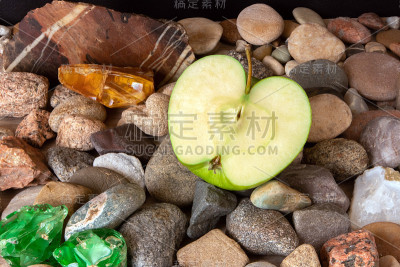 半只绿苹果，茎在卵石上