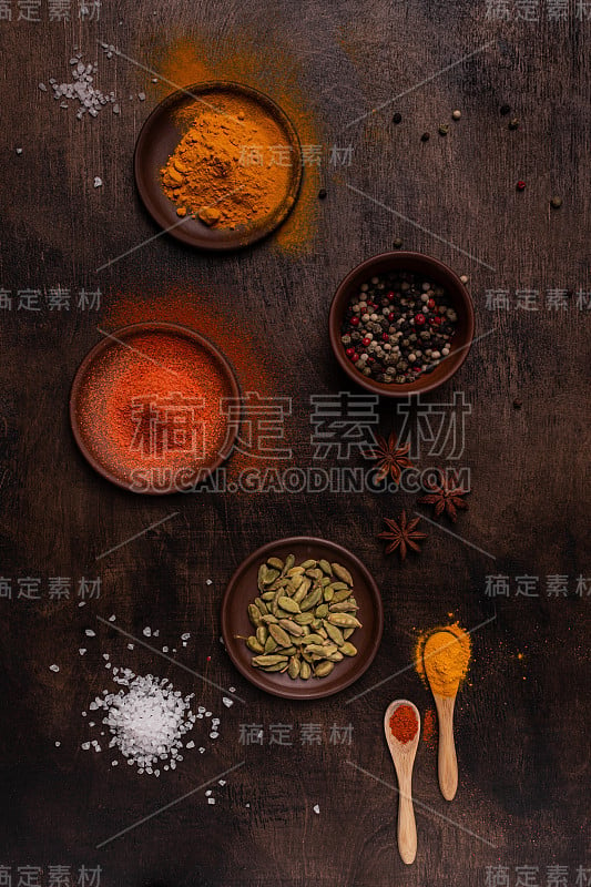 红辣椒，胡椒粉，豆蔻，盐和姜黄粉平铺在木质背景上