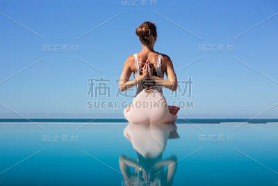 在泳池边做瑜伽的女人。