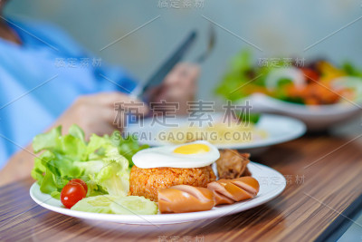 亚洲老年人或老年妇女妇女病人吃早餐蔬菜健康食物与希望和快乐而坐在床上饥饿在医院。