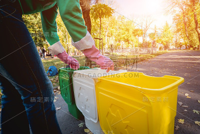 志愿者女孩在公园的街道上分类垃圾。回收的概念。