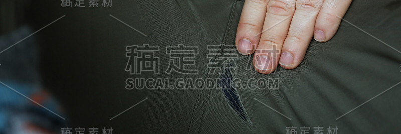 男人叉开双腿，露出裤子上的洞