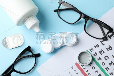 眼镜，隐形眼镜和视力检查表在蓝色背景，俯视图