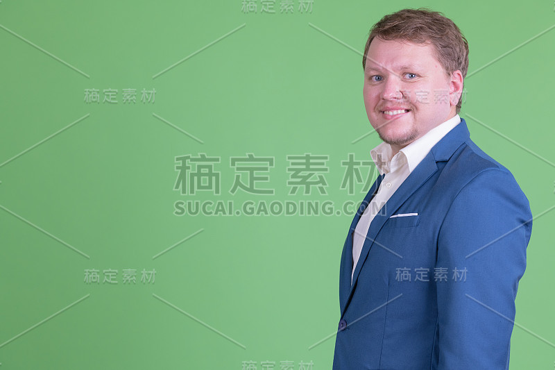 快乐超重大胡子商人的侧面图看着相机