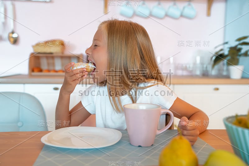 可爱的小女孩早上在家吃早餐，喝茶吃甜甜圈。美味的食物。