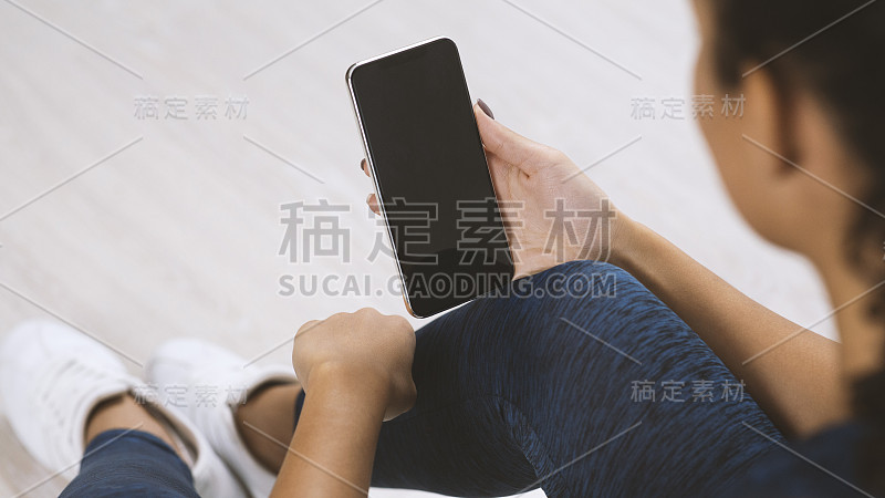 年轻的运动女人拿着手机与空白屏幕室内，近距离观看。模型设计