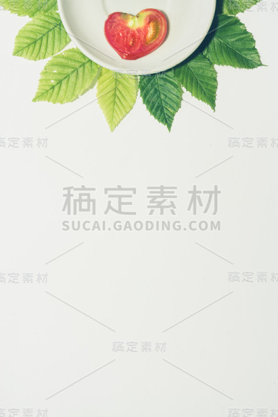 最小的心形番茄切片背景。水果放在白色盘子里，周围是树叶。哑光色。垂直封面，横幅，传单，传单，页面设计