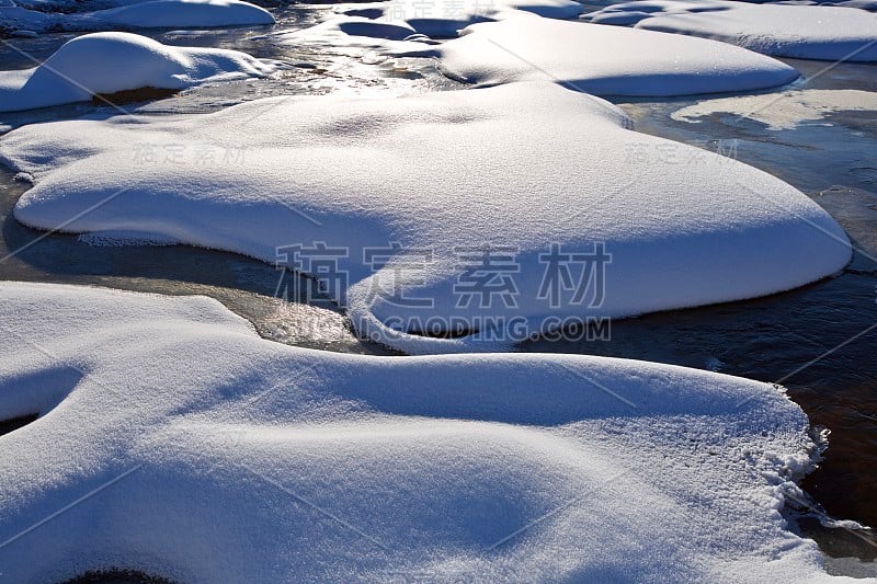 雪堆在结冰的小溪上