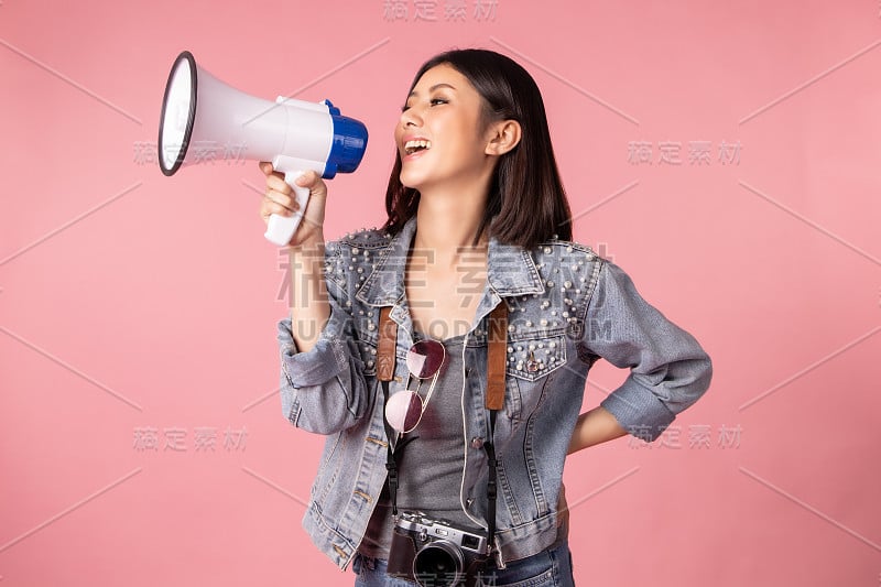 夏日休闲装的女游客。亚洲微笑的女子。以粉红色为背景出国旅行的乘客。她要去度暑假了。假日信用卡。