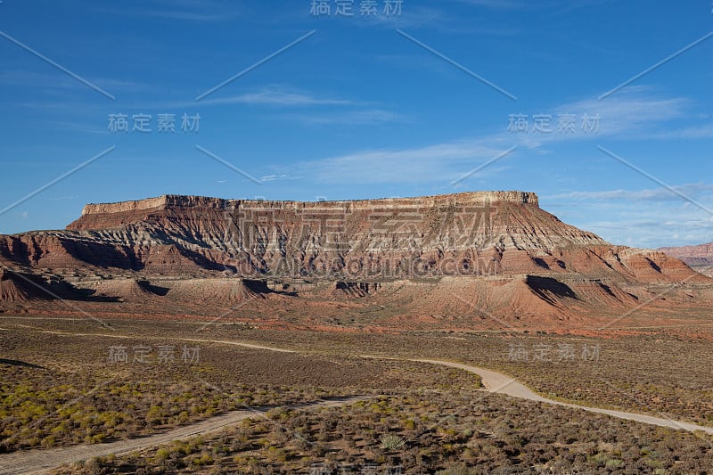 令人惊叹的峡谷形状像一个自然剧院在背景，土路交叉在前景的沙漠