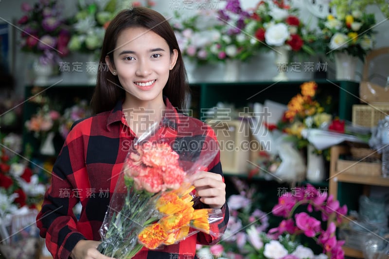 微笑的女人花店小商花店老板和年轻花店检查花在商店