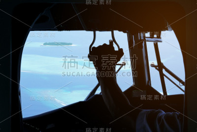 从水上飞机座舱内眺望明亮的著名海滩目的地马尔代夫小岛环礁。飞机内部是黑暗的，所以我们可以看到飞行员的