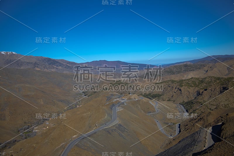 弯弯曲曲的道路穿梭于群山之间，背景是清澈的蓝天