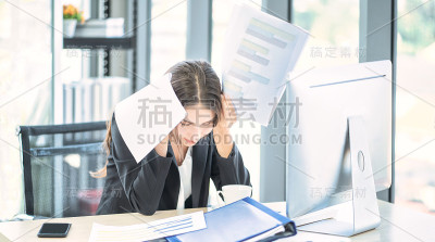 用笔记本电脑和文件在办公室工作的女商人。头疼的女人。疲惫和担忧的女商人在办公室工作。压力和抑郁。