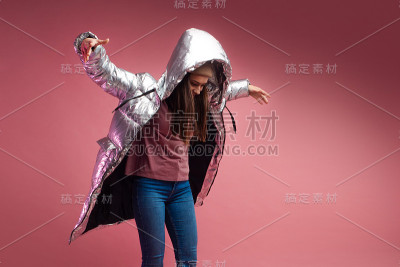 时尚和现代的年轻女子在一个蓬松的轻羽绒服扔在她的头上兜帽。