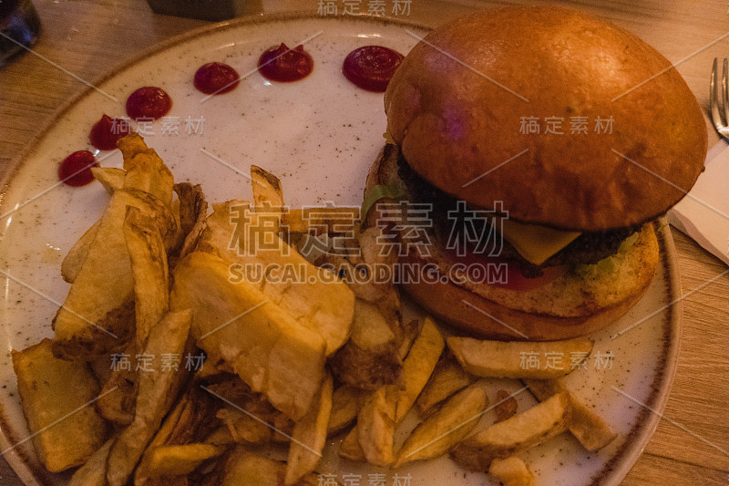 牛肉饼、黑面包、生菜和蕃茄酱放在质朴的木桌上，配上炸薯条