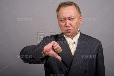 在灰色背景下拍摄成熟的亚洲商人