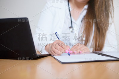 特写的年轻女医生坐在桌子后面填写表格