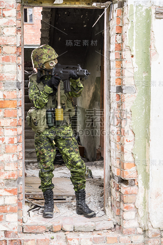 身着迷彩服的武装女子的肖像。年轻的女兵用枪观察。儿童兵带着枪和防毒面具在战争炉膛，房子废墟的背景。军