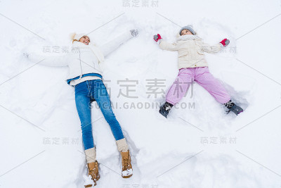 母亲和女儿做雪天使和微笑
