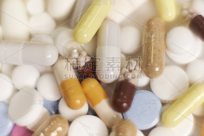 不同种类的药丸以慢镜头落在白色背景上。多种颜色的平板电脑正在飞速发展。漂亮的滴丸在桌子上。医疗